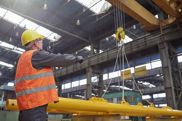 Männlicher Arbeiter, der einen hydraulischen Kran in einer Fabrik führt - CAIF07289