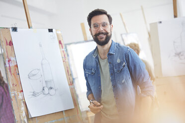 Porträt lächelnder männlicher Künstler mit Bart beim Skizzieren im Atelier einer Kunstklasse - CAIF07292