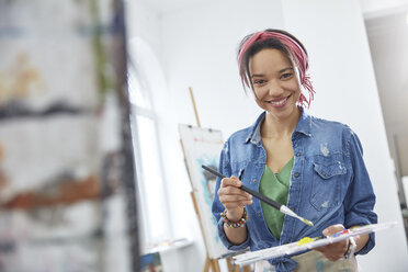 Porträt lächelnde Künstlerin mit Pinsel und Palette, Malen im Atelier der Kunstklasse - CAIF07304