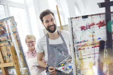 Porträt lächelnde Künstler malen an Staffeleien im Atelier des Kunstunterrichts - CAIF07314