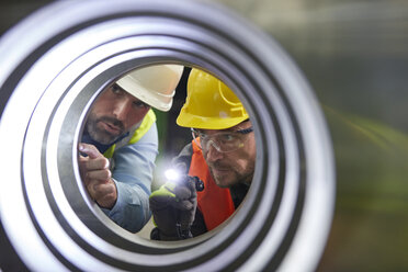 Serious male engineers with flashlights examining steel pipe - CAIF07323