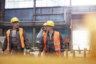 Männliche Arbeiter gehen in einer Fabrik - CAIF07328