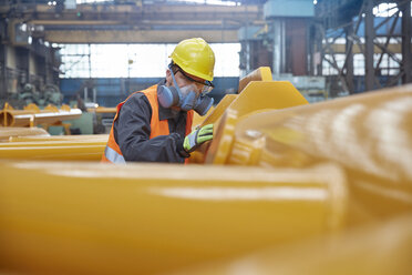 Steel worker wearing protective face mask, examining equipment in steel factory - CAIF07331