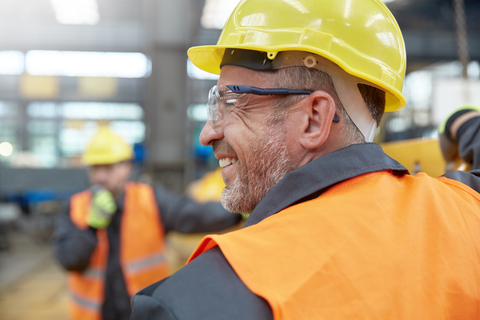 Profil lächelnder männlicher Arbeiter in einer Fabrik, lizenzfreies Stockfoto