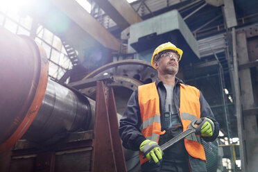 Confident male worker holding wrench in factory - CAIF07339