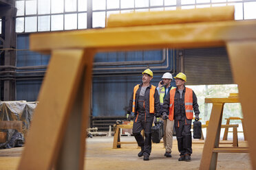 Männliche Arbeiter gehen in einer Stahlfabrik - CAIF07352