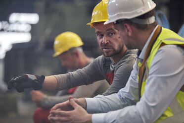 Männliche Arbeiter unterhalten sich in einer Fabrik - CAIF07358