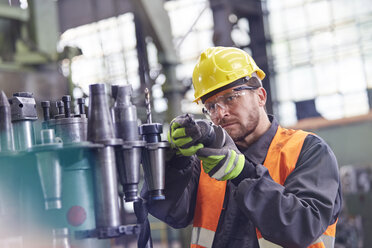 Männlicher Arbeiter bei der Prüfung von Stahlteilen in einer Fabrik - CAIF07360