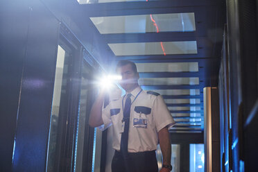 Männlicher Wachmann mit Taschenlampe im Serverraum - CAIF07366