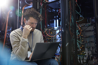 Fokussierter männlicher IT-Techniker mit Laptop im Serverraum - CAIF07394