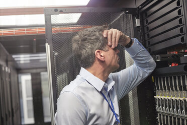 Frustrated IT technician at panel in server room - CAIF07408