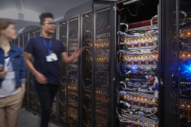 IT technicians walking along panels in server room - CAIF07422