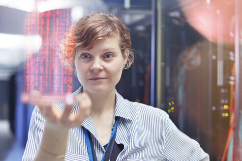 Female IT technician holding futuristic digital tablet in server room - CAIF07428