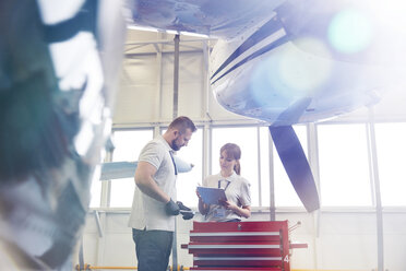 Flugzeugmechaniker mit Klemmbrett im Gespräch am Werkzeugkasten im Hangar - CAIF07439