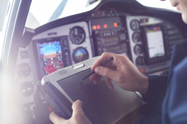 Flugzeugpilot benutzt einen Stift auf einem digitalen Tablet im Cockpit - CAIF07444