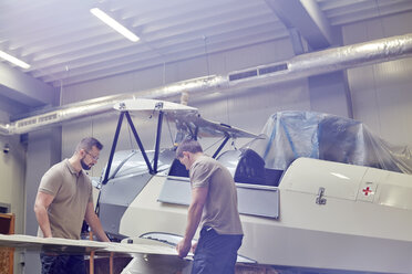 Männliche Ingenieure beim Zusammenbau eines Flugzeugs in einem Hangar - CAIF07449