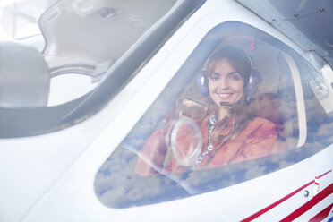 Portrait smiling female airplane pilot in cockpit - CAIF07452