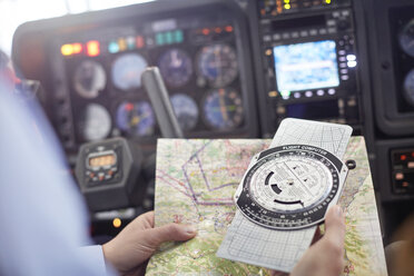 Pilot prüft Navigationskarte und Kompassinstrument im Cockpit eines Flugzeugs - CAIF07455