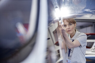 Fokussierter weiblicher Ingenieur-Mechaniker bei der Untersuchung eines Flugzeugs - CAIF07460