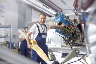 Portrait confident male engineer mechanic working on airplane in hangar - CAIF07461