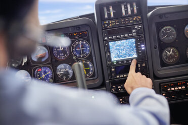 Männlicher Pilot mit Navigationsinstrumenten im Cockpit eines Flugzeugs - CAIF07467