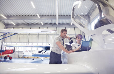 Mechaniker bei der Arbeit im Cockpit eines Flugzeugs im Hangar - CAIF07471