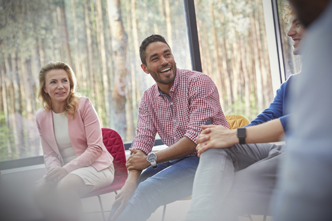 Lächelnder Mann hört in einer Gruppentherapiesitzung zu, lizenzfreies Stockfoto