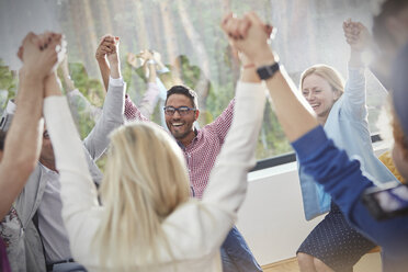 Lächelnde und sich an den Händen haltende Menschen im Kreis in einer Gruppentherapiesitzung - CAIF07505