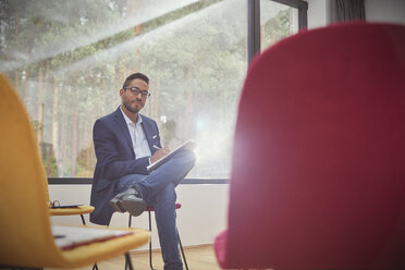 Portrait confident businessman writing on clipboard in office - CAIF07506