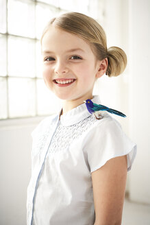 Porträt eines glücklichen kleinen Mädchens mit Spielzeugvogel auf der Schulter - FSF00993