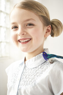 Porträt eines glücklichen kleinen Mädchens mit Spielzeugvogel auf der Schulter - FSF00997
