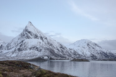 Schneebedeckte Berge entlang eines kalten Sees, Lofoten-Inseln, Norwegen - CAIF07511