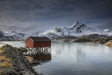 Schneebedeckte Berge hinter der Fischerhütte über dem See, Sund, Lofoten-Inseln, Norwegen - CAIF07516