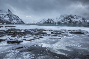 Schneebedeckte Berge hinter kaltem Meer, Vareid, Lofoten, Norwegen - CAIF07524