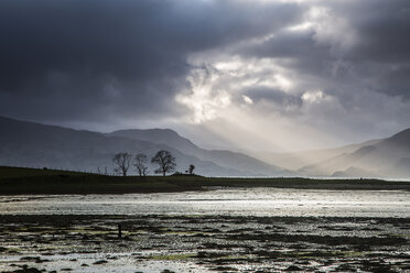 Sonnenstrahlen am stürmischen Himmel über einem See, Schottland - CAIF07542