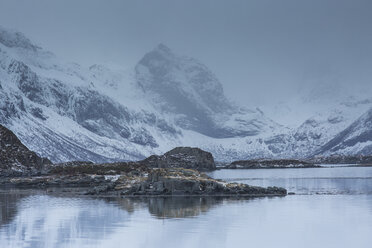 Schneebedeckte zerklüftete Berge über einer kalten Bucht, Norwegen - CAIF07543