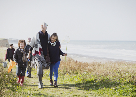 Multi-generation family walking on grassy beach path stock photo