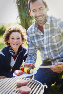 Portrait lächelnder Vater und Sohn beim Grillen - CAIF07556