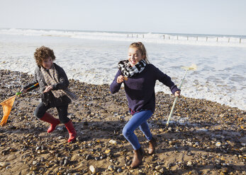 Bruder und Schwester mit Netzen, die vom Meer auf den Strand laufen - CAIF07568