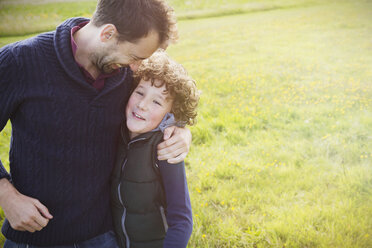 Father hugging son in field - CAIF07570