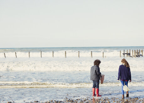 Brother and sister with nets in ocean surf - CAIF07574