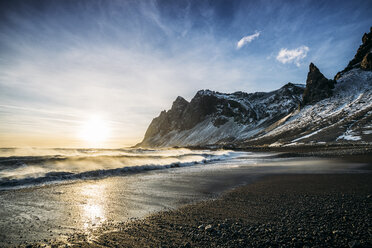 Sonnenuntergang über einem ruhigen Strand und verschneiten Bergen, Island - CAIF07612