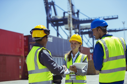 Geschäftsleute und Arbeiter unterhalten sich in der Nähe von Frachtcontainern, lizenzfreies Stockfoto