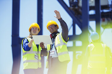 Businessman and worker talking near cargo crane - CAIF07655