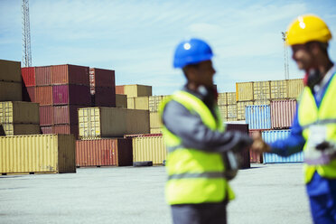 Arbeiter und Geschäftsmann geben sich in der Nähe von Frachtcontainern die Hand - CAIF07660