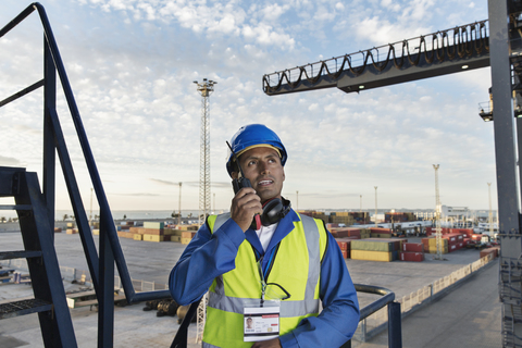 Arbeiter mit Walkie-Talkie auf einem Frachtkran, lizenzfreies Stockfoto