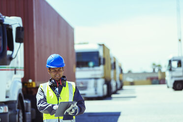 Arbeiter mit digitalem Tablet in der Nähe von Lastwagen mit Frachtcontainern - CAIF07672