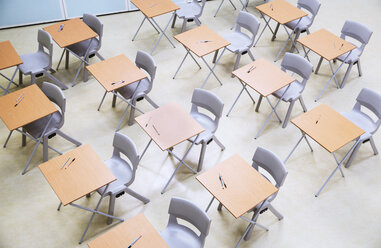 Erhöhte Ansicht von Reihen von Tischen und Stühlen in einem leeren Klassenzimmer - CAIF07677
