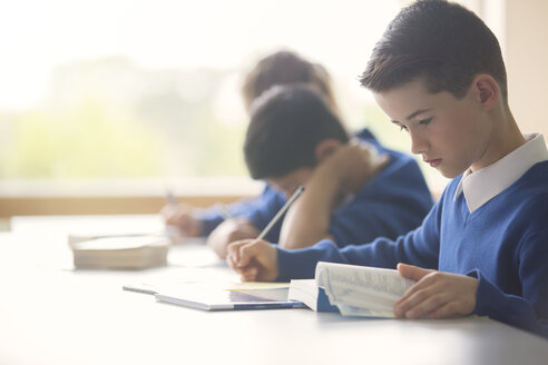 Schüler lernen im Klassenzimmer mit Buch und Tablet-PC - CAIF07679