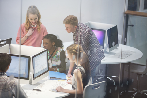 Lächelnde Schüler beim Lernen im Computerraum, lizenzfreies Stockfoto